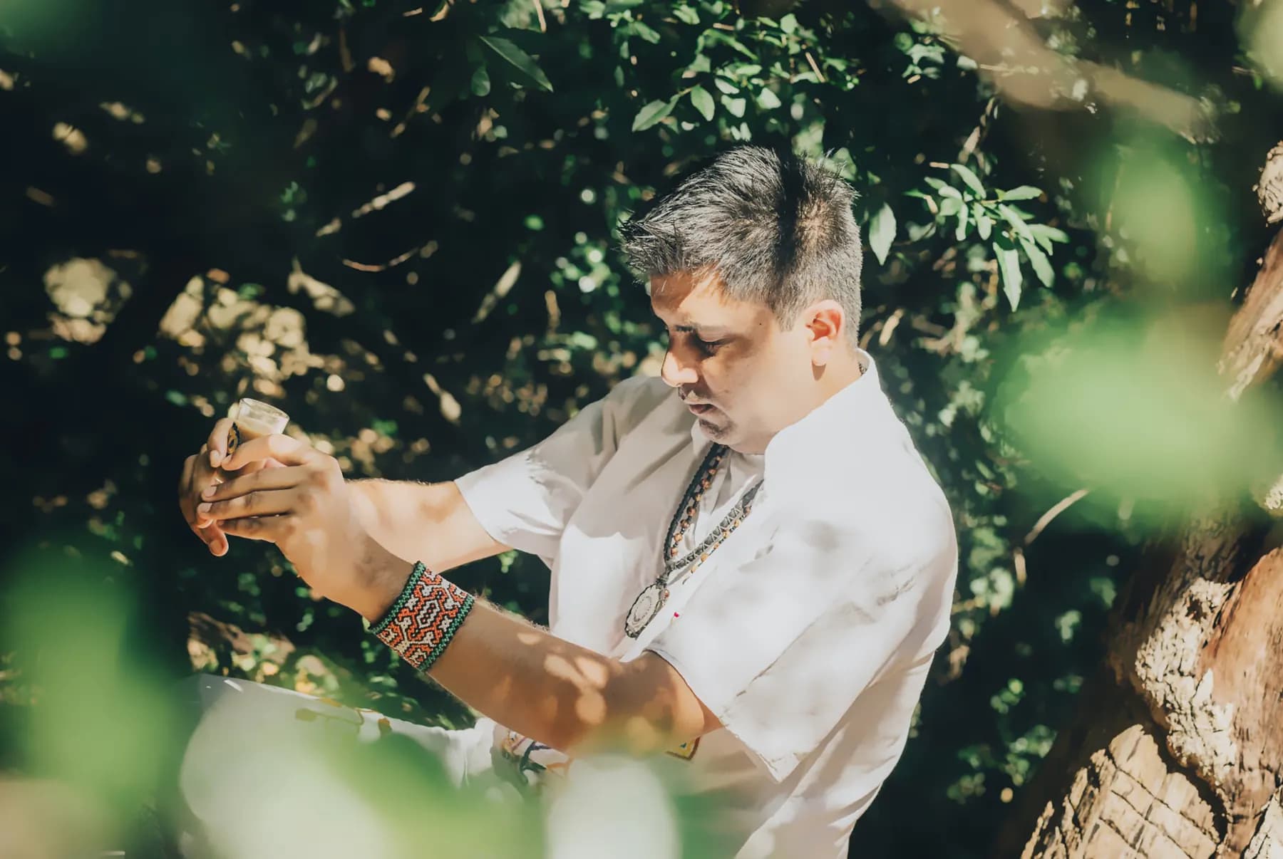 Jayesh Mitha holding a ceremonial cup of Ayahuasca among the trees